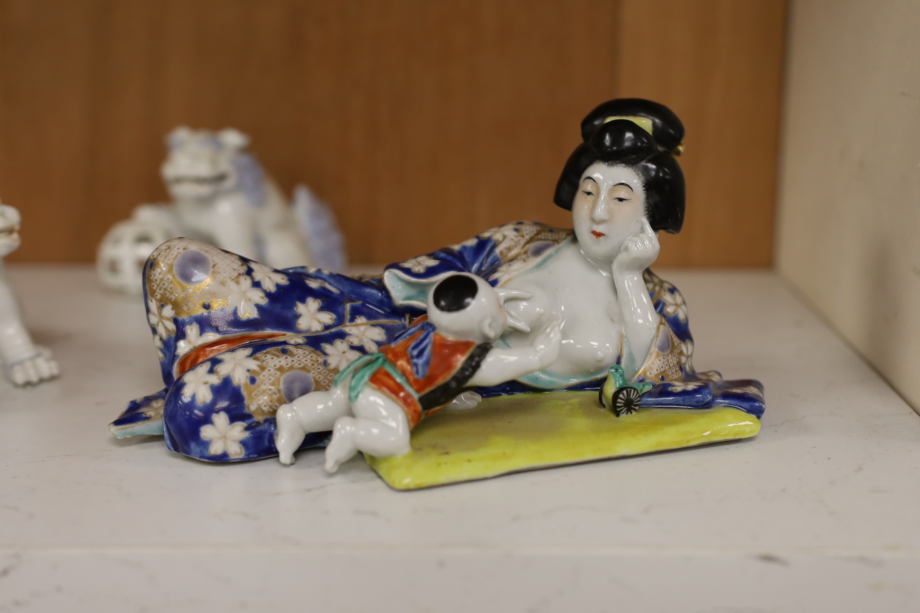 A Japanese enamelled reclining figure of mother and baby and two Hirado style shi-shi figures, reclining figure group 21cm wide. Condition - good